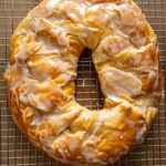 Freshly baked Wisconsin Apple Kringle with vanilla glaze cooling on a wire rack.